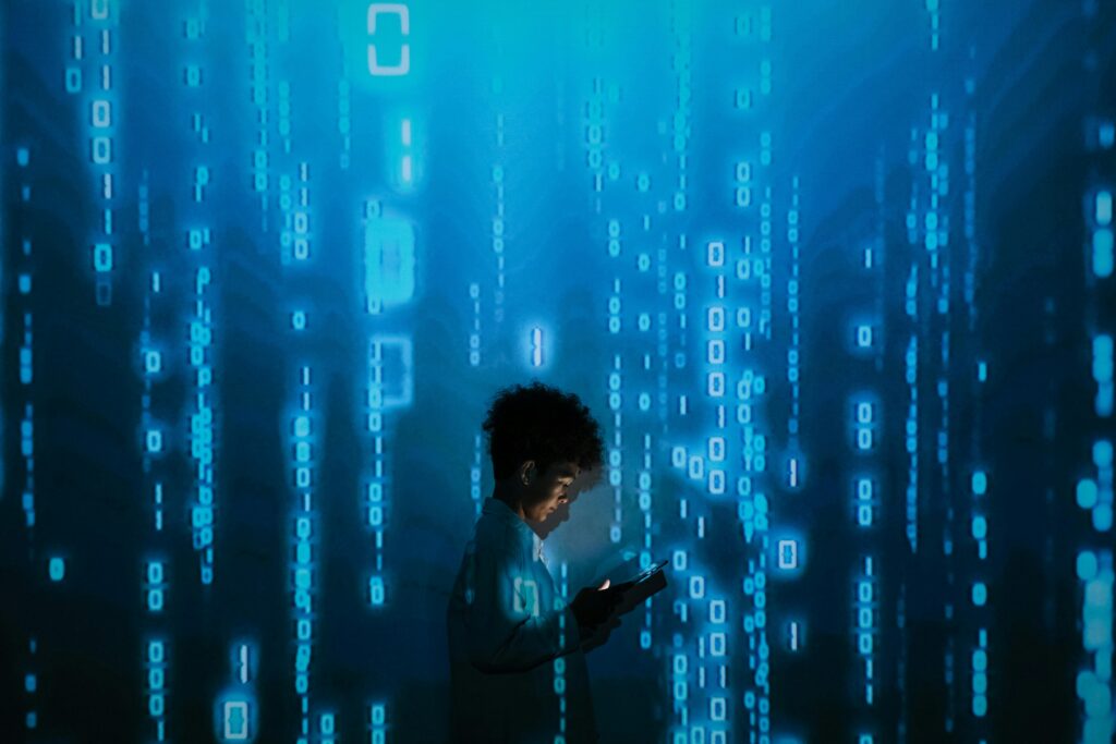 pexels-photo-9783812-9783812 Silhouette of a person using a smartphone surrounded by digital binary code projections.