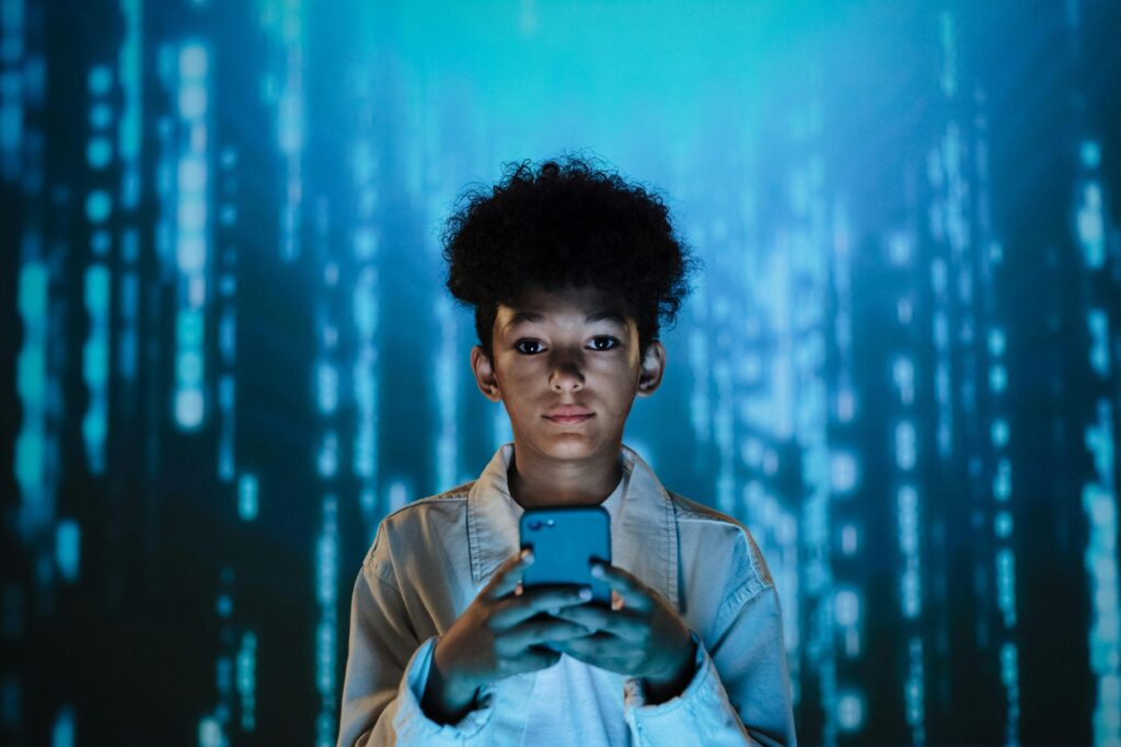 A teenager holds a smartphone surrounded by a futuristic digital backdrop.